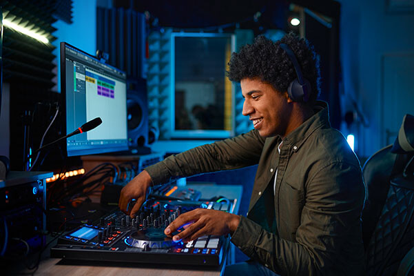 A smiling young black man mixing audio in a professional studio.