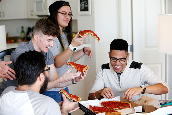 USV students in one of their apartments; living rooms, sharing a pizza.